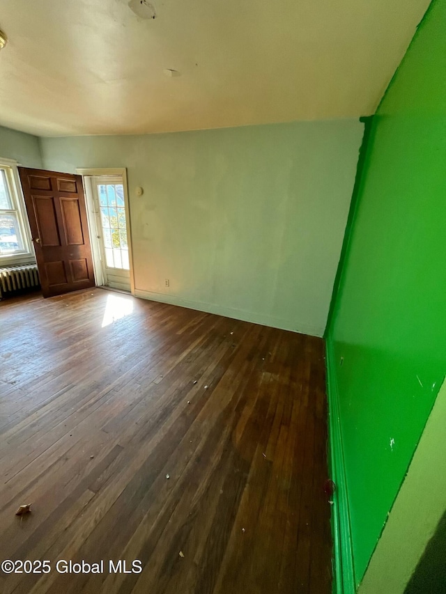 interior space featuring radiator heating unit, baseboards, and dark wood finished floors