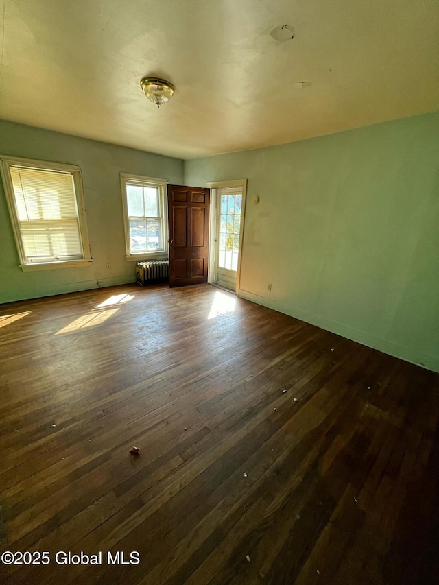 spare room with dark wood-style flooring, radiator, and baseboards