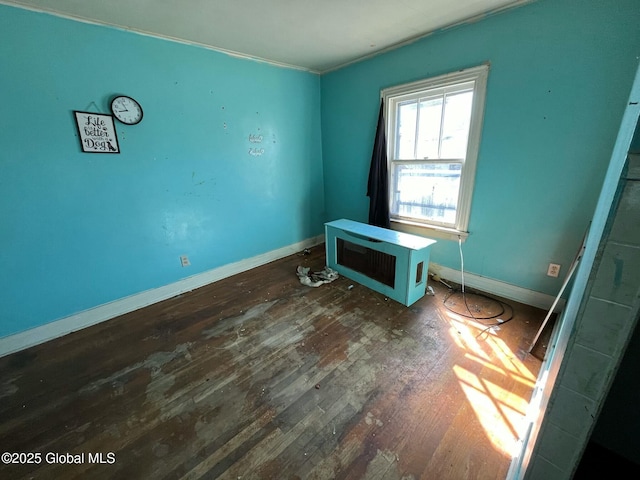 unfurnished room featuring dark wood-style flooring, crown molding, and baseboards