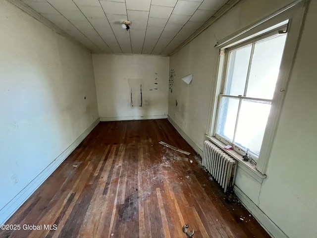 empty room featuring wood-type flooring, plenty of natural light, and radiator
