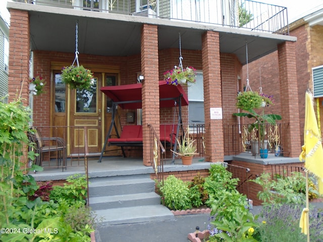 doorway to property featuring a porch and brick siding