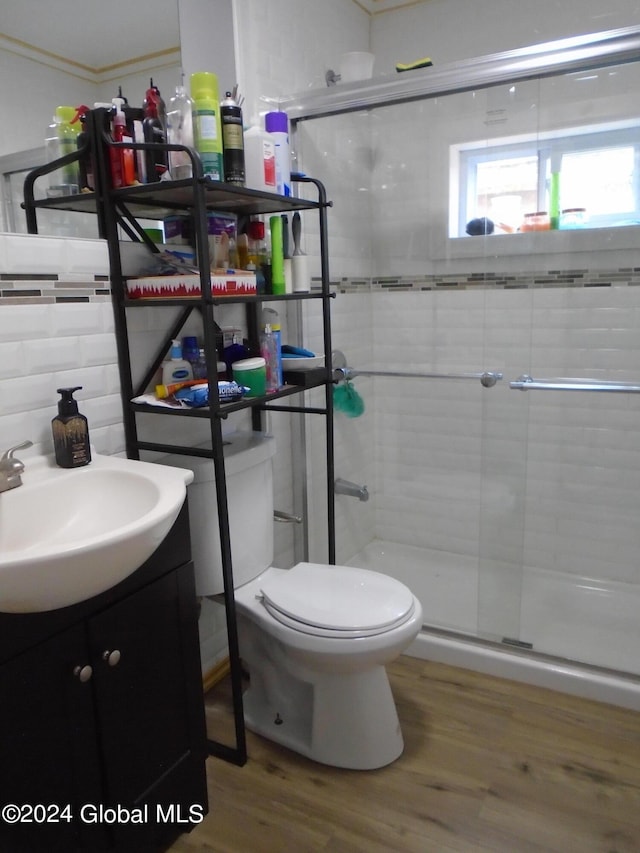 full bathroom featuring a shower stall, tile walls, toilet, wood finished floors, and vanity