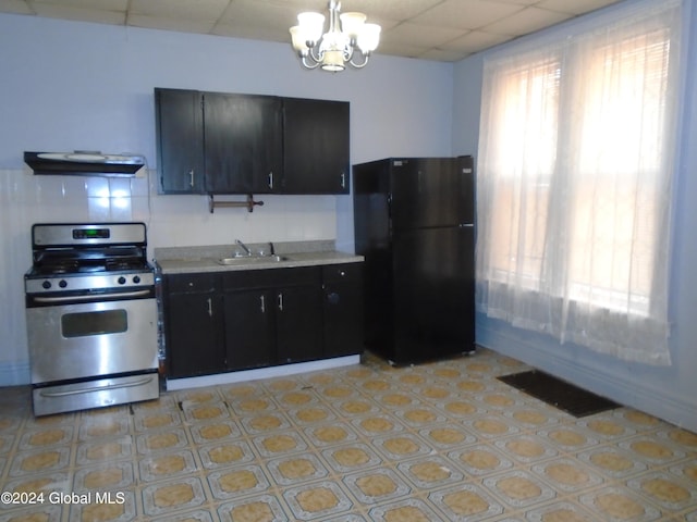 kitchen with visible vents, under cabinet range hood, stainless steel range with gas stovetop, freestanding refrigerator, and a sink