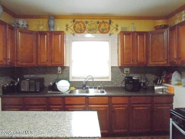 kitchen with a sink, range with electric stovetop, backsplash, and black microwave