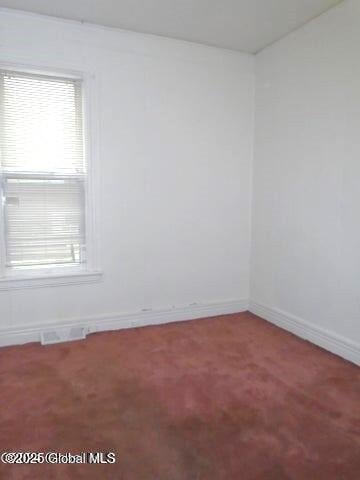 carpeted spare room with visible vents and baseboards