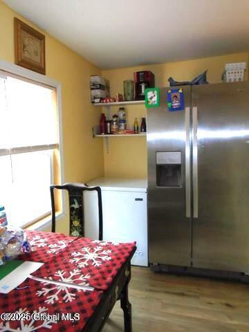 kitchen featuring light wood finished floors, stainless steel fridge with ice dispenser, light countertops, vaulted ceiling, and fridge