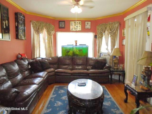 living area featuring plenty of natural light, crown molding, and wood finished floors