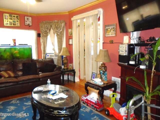 living room with wood finished floors and crown molding