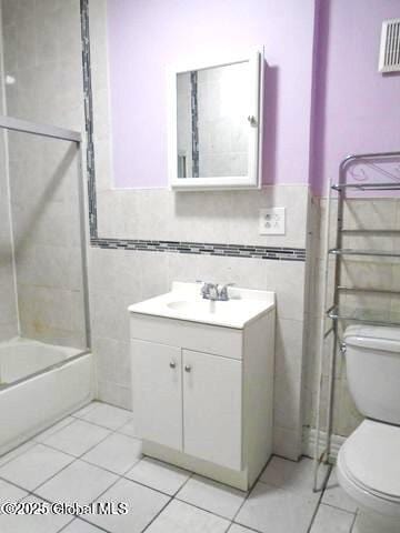 full bathroom featuring tile patterned floors, toilet, vanity, and tile walls