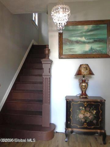 staircase featuring a notable chandelier and wood finished floors