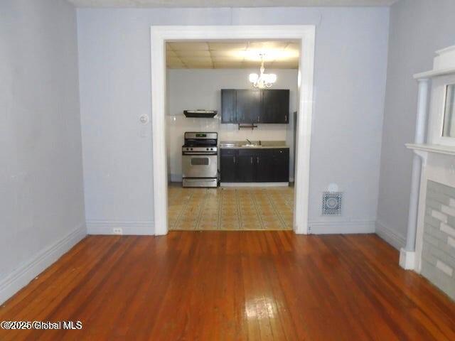 interior space with visible vents, a sink, wood finished floors, an inviting chandelier, and baseboards