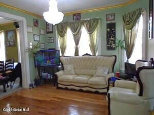 living room with crown molding and wood finished floors