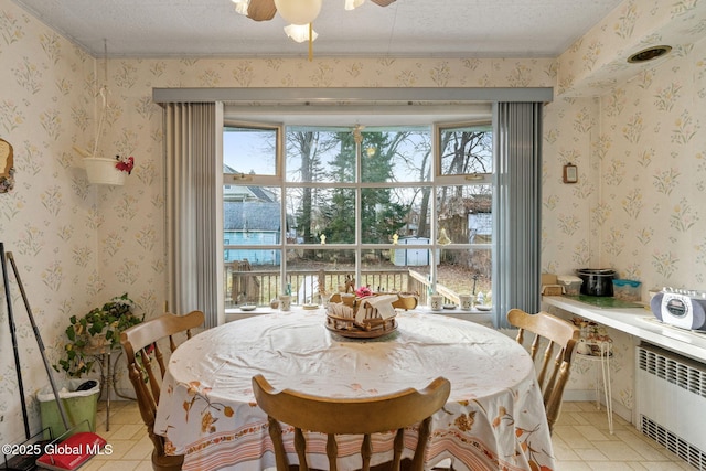 dining room featuring a textured ceiling, radiator heating unit, and wallpapered walls