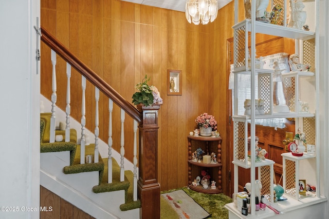 staircase with a notable chandelier and wood walls