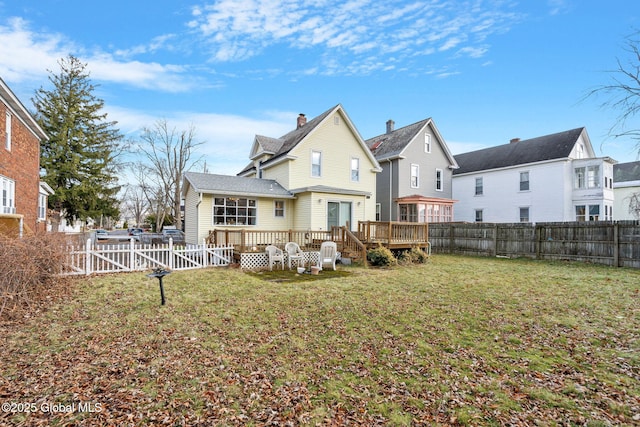 rear view of property featuring a wooden deck, a lawn, a fenced backyard, and a gate