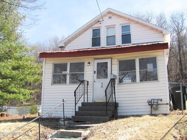 bungalow with metal roof, fence, and entry steps