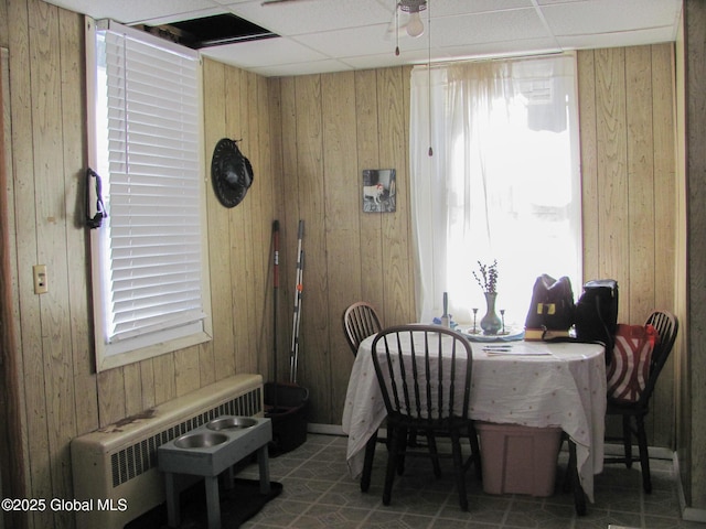 dining room featuring plenty of natural light, wood walls, and radiator heating unit