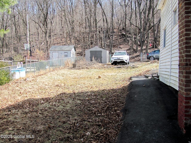 view of yard with a storage shed, an outdoor structure, and fence