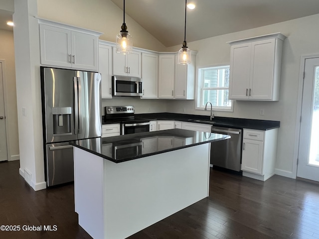 kitchen with dark wood-style floors, a sink, stainless steel appliances, white cabinets, and dark countertops