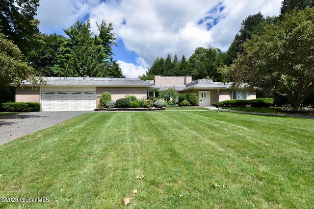 single story home with aphalt driveway, an attached garage, brick siding, and a front yard