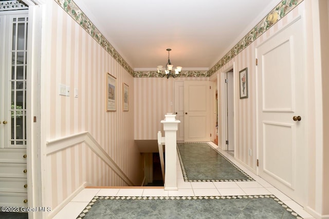 hall with tile patterned floors, an inviting chandelier, wainscoting, and wallpapered walls