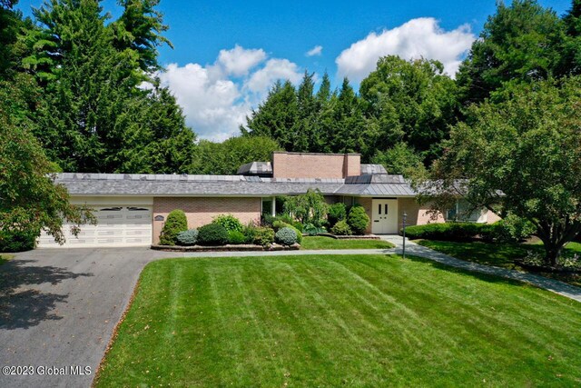 view of front of home featuring brick siding, aphalt driveway, an attached garage, and a front yard