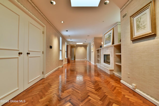 hallway with visible vents, baseboards, ornamental molding, recessed lighting, and a skylight