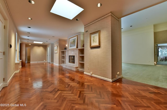 unfurnished living room featuring baseboards, ornamental molding, recessed lighting, a tile fireplace, and a skylight