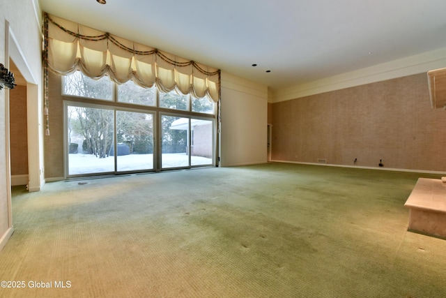 unfurnished living room with baseboards, a high ceiling, and carpet flooring