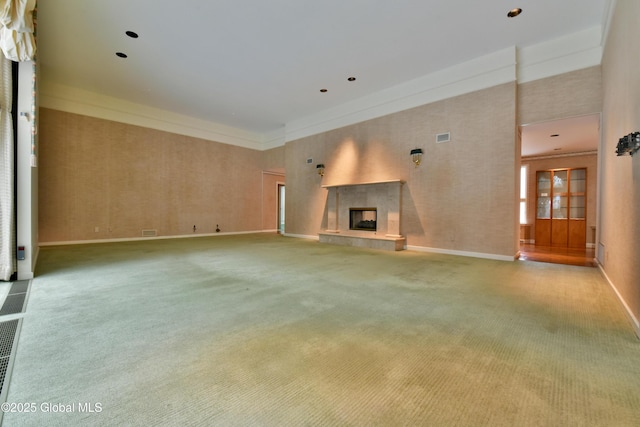 unfurnished living room featuring visible vents, a tile fireplace, baseboards, and carpet floors