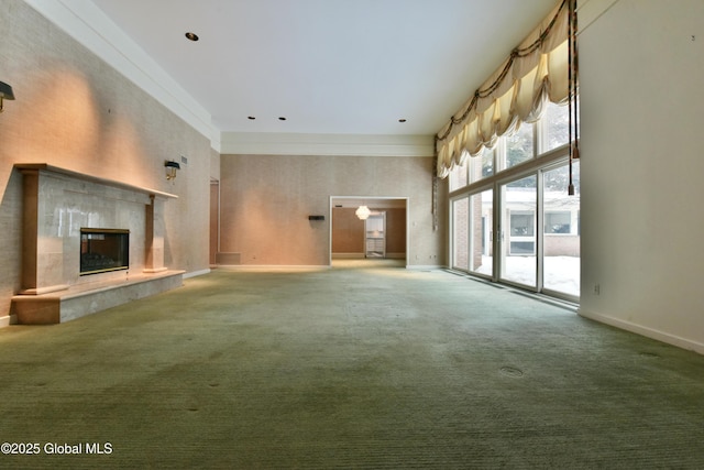 unfurnished living room featuring carpet, a fireplace, baseboards, and a towering ceiling