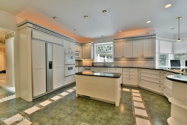 kitchen with dark countertops, tasteful backsplash, pendant lighting, recessed lighting, and white appliances