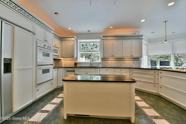 kitchen featuring recessed lighting, white appliances, dark countertops, and a sink