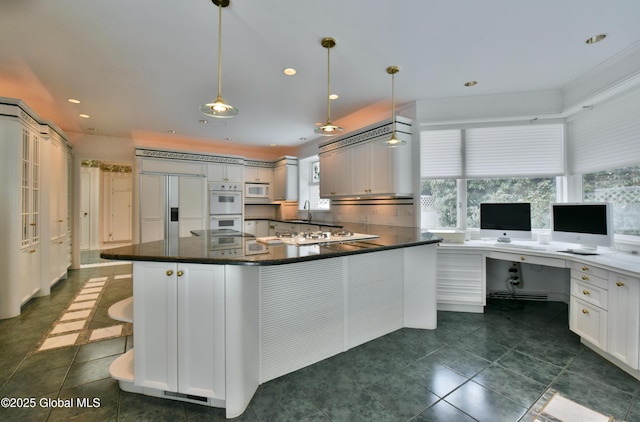 kitchen with white appliances, dark countertops, built in desk, and tasteful backsplash