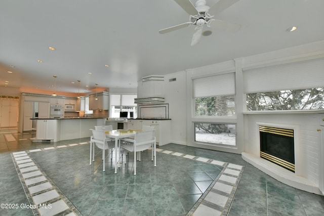 unfurnished dining area featuring recessed lighting, a fireplace, and ceiling fan