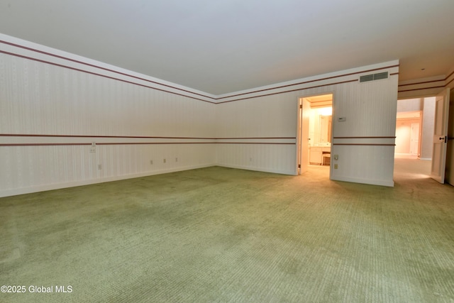 carpeted empty room featuring visible vents and wallpapered walls