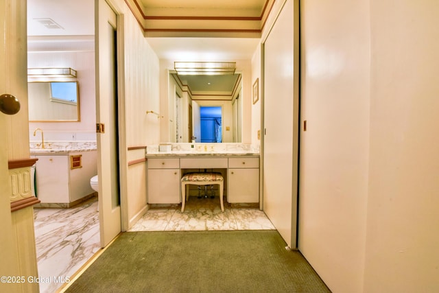 corridor with marble finish floor, light colored carpet, and a sink