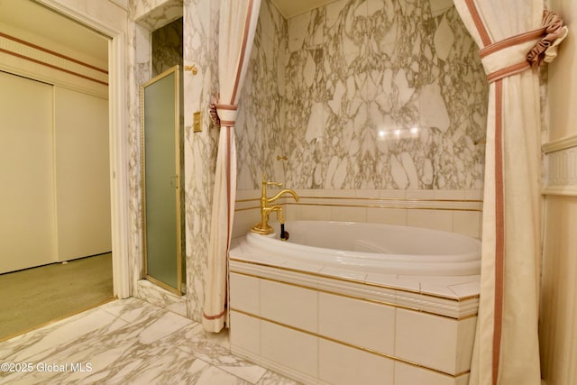 full bath featuring marble finish floor, a stall shower, and a bath