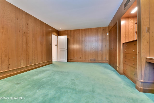 carpeted empty room with wood walls