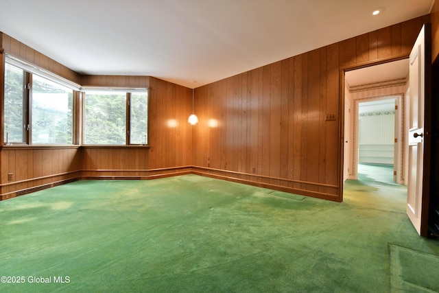 carpeted empty room featuring wooden walls