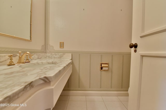 bathroom with tile patterned floors, wainscoting, and a sink