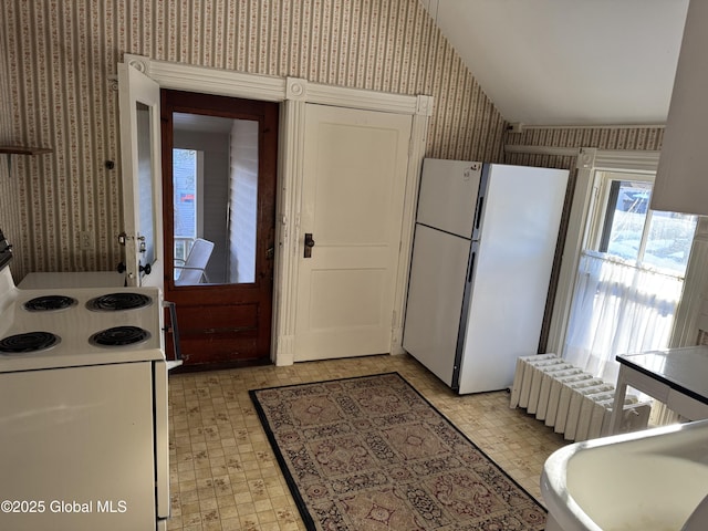 kitchen with radiator heating unit, white appliances, wallpapered walls, lofted ceiling, and light floors