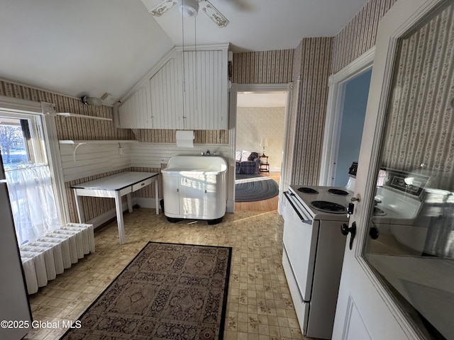 kitchen featuring wallpapered walls, vaulted ceiling, electric stove, and light floors