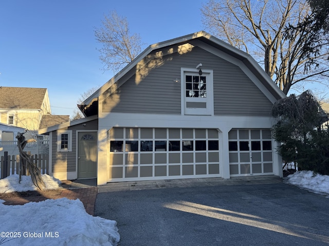 exterior space with a detached garage, fence, and a gambrel roof