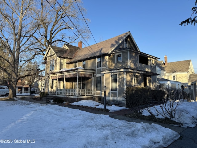 victorian home with a balcony, covered porch, and a chimney