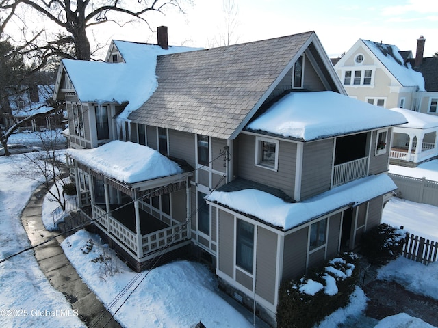 snow covered property with a chimney and fence