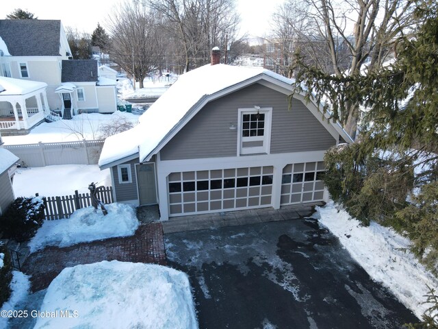 colonial inspired home with a gambrel roof, driveway, a chimney, and fence