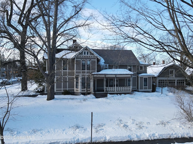 snow covered property with a chimney and a sunroom