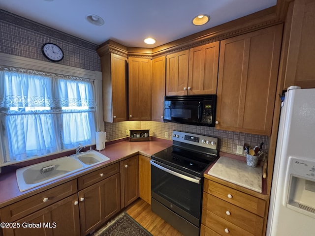 kitchen with decorative backsplash, a sink, white refrigerator with ice dispenser, black microwave, and stainless steel electric range oven