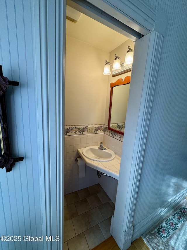 bathroom with tile patterned floors, a wainscoted wall, tile walls, and a sink